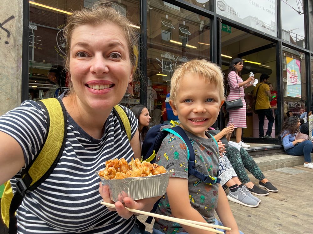 Paola Bertoni e figlio che mangiano pollo fritto in agrodolce di una bancarella di street food dell'Upmarket di Brick Lane, Londra