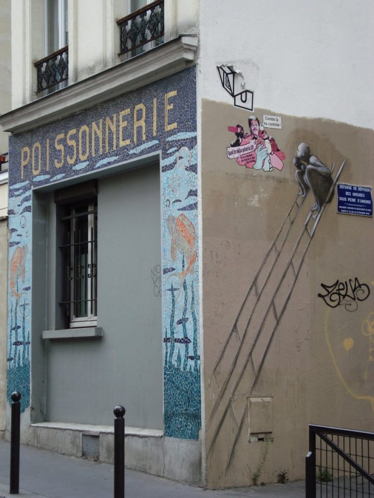 Mosaico intorno alla vecchia entrata di un pescivendolo e murales nel quartiere Belleville di Parigi